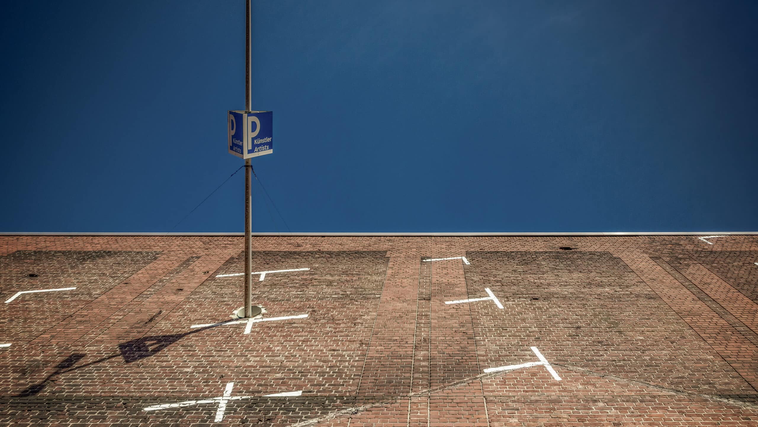 Steiler Blick auf einen Künstlerparkplatz unter tiefblauem Himmel.