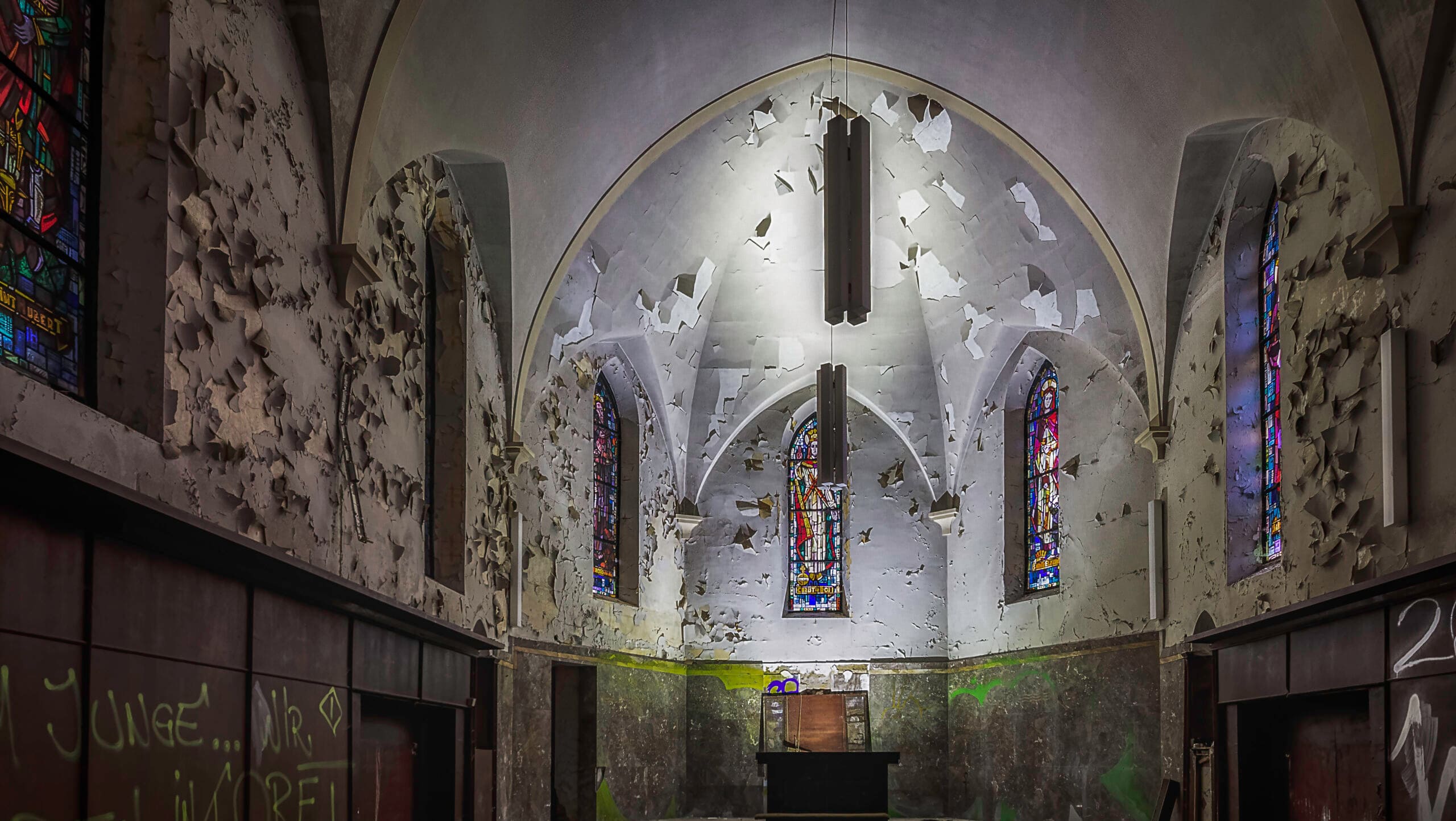Verlassene Kirche mit Graffiti und bröckelndem Putz.