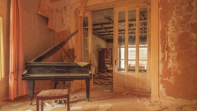 Verlassenes Zimmer mit Klavier und Notenblättern.