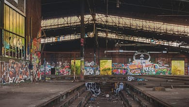 Verlassene Industriehalle mit Graffiti und Müll.